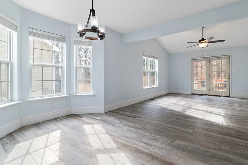 Empty living room with large windows and sunlight on the floor